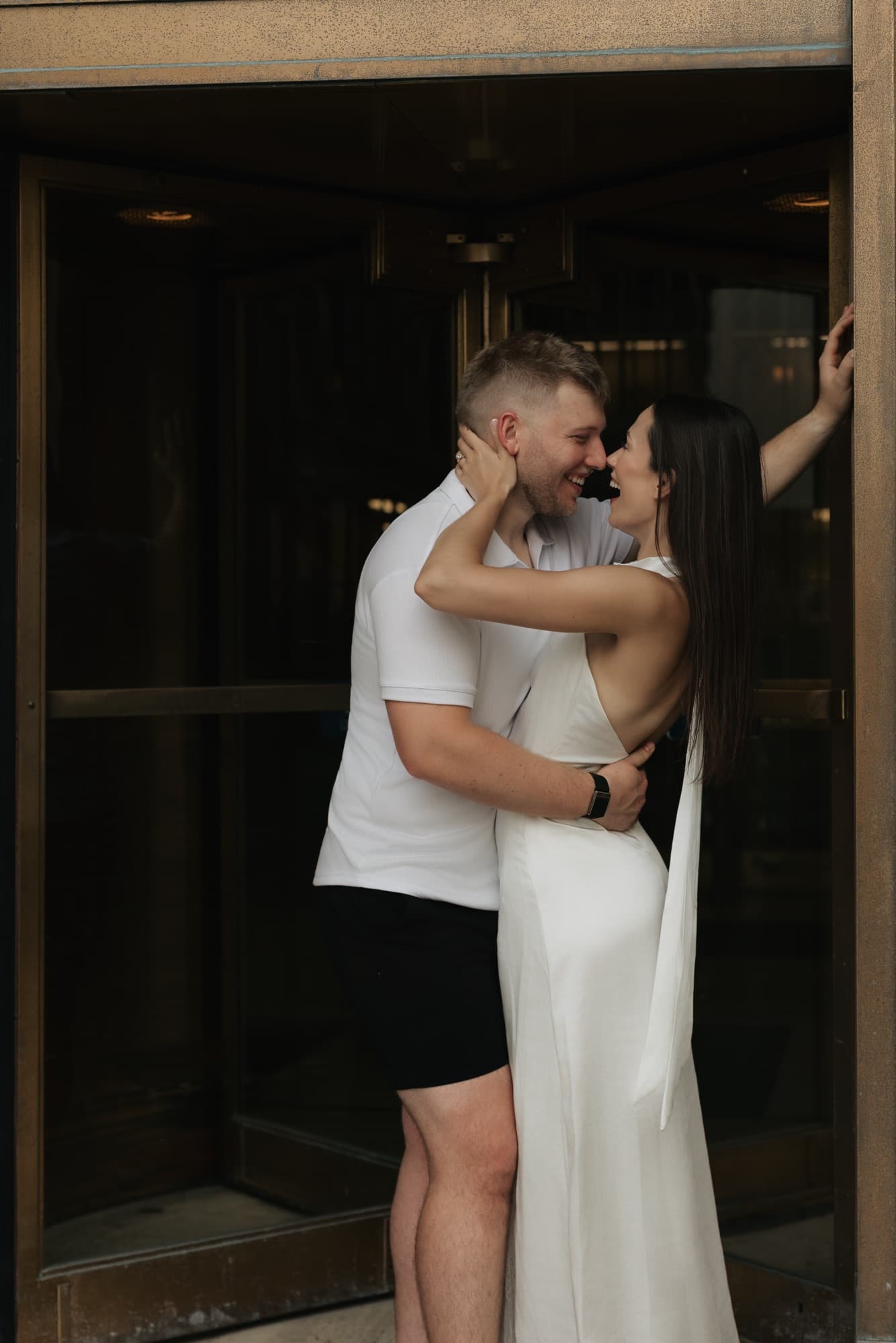 Andrew and Madeline laughing together in the bronze revolving doorway of Lincoln Tower